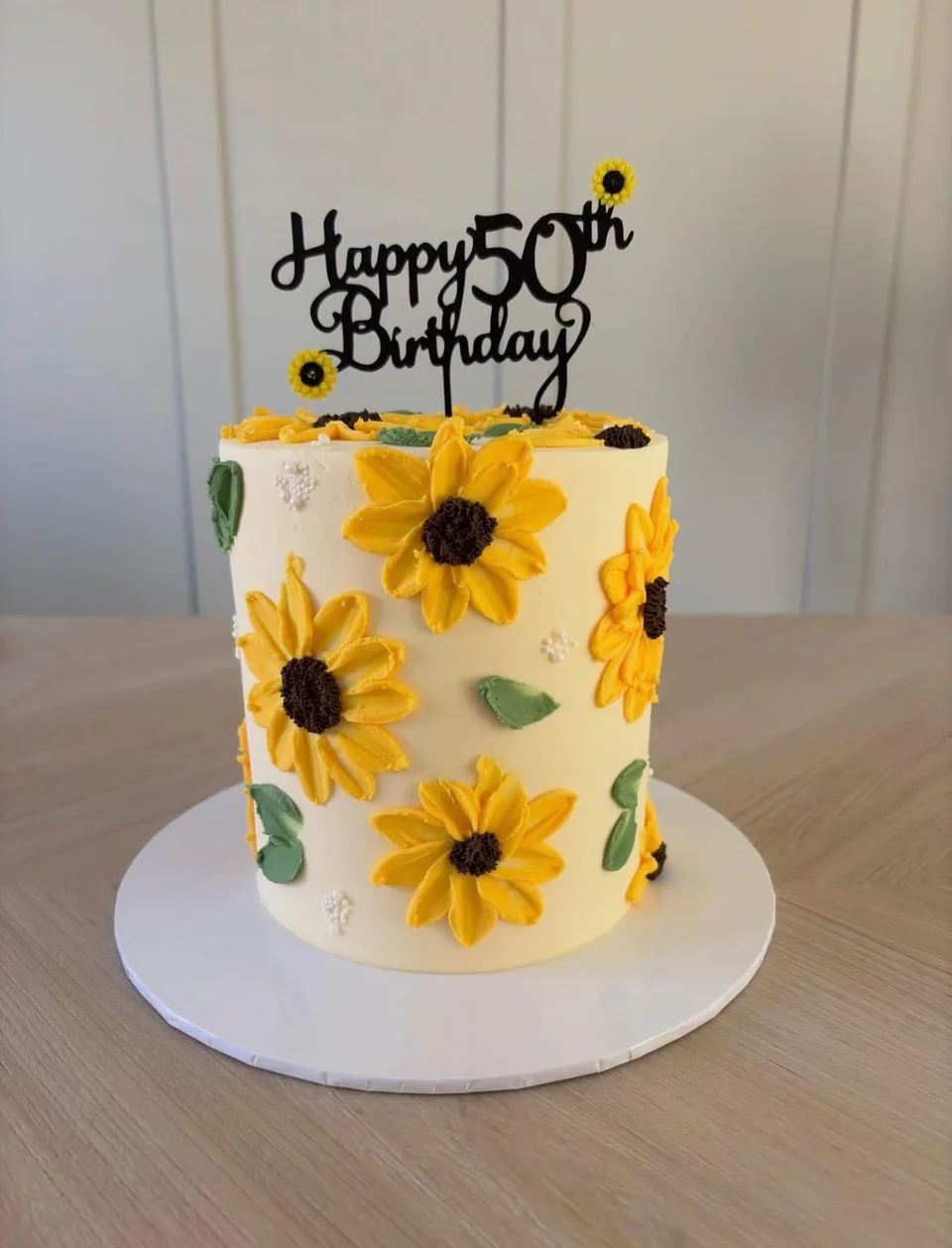 Ivory fiftieth birthday cake covered in bright yellow sunflowers